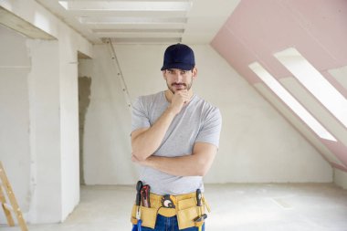 Onun çene ayakta inşaat sahasında üzerinde el ile genç düşünme el işleri ustası. 