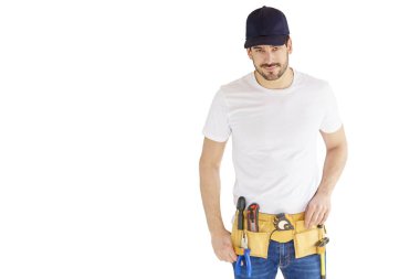 Yakışıklı genç tamirci izole beyaz arka plan kopya alanı ile duran beyzbol kap ve aracı kemer takmaya portresi.