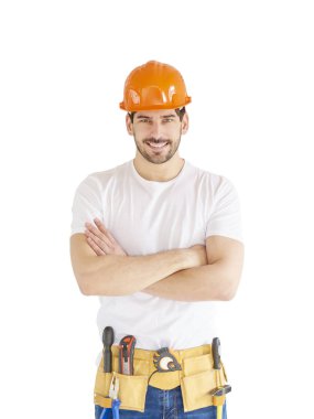 Portrait of young handyman wearing hard hat and tool belt while standing with arms crossed at isolated white background with copy space. clipart