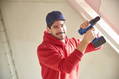 Genç tamirci inşaat alanındaki çekiç matkap sürücüyü kullanarak portresi. 