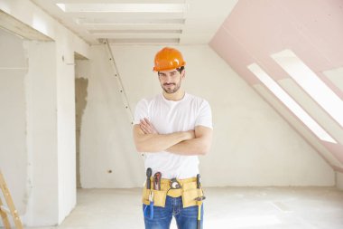 Portre gelen genç adamdır kask ve alet kemeri duran kolları olan inşaat alanında geçti. 