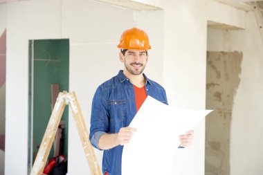 Mutlu mühendis holding planı elinde duran inşaat alanı, portre.