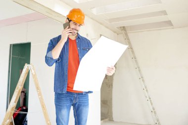 Portre gelen genç adamdır elini tutarak blueprint ve duran inşaat alanı, arama yapma.