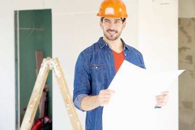 Genç tamirci holding planı elinde duran inşaat alanı, portre. 