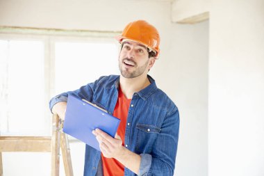 Elinde duran inşaat alanı, kask ve holding panoya giyen genç tamirci portresi.