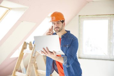 Dizüstü bilgisayar ve cep telefonu dururken yenileme alanı kullanarak genç tamirci.