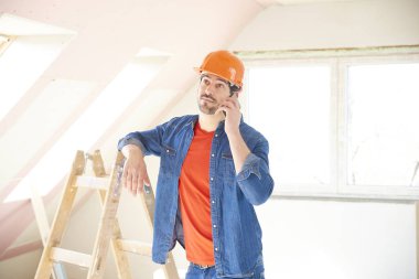 Yakışıklı genç tamirci evde duran ve iç tamir çalışma sırasında cep telefonunu kullanma.
