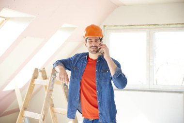 Yakışıklı genç tamirci evde duran ve iç tamir çalışma sırasında cep telefonunu kullanma.