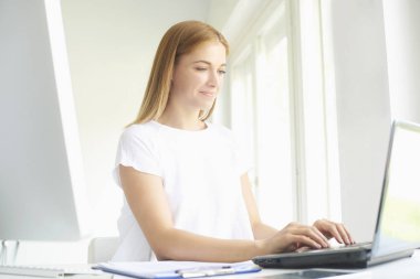 Güzel genç satış kadının modern ofiste yeni proje üzerinde çalışırken dizüstü bilgisayarda yazarak atış. 