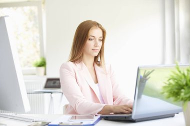 Modern ofiste oturan ve dizüstü bilgisayarda çalışma güzel genç iş kadını portresi. 