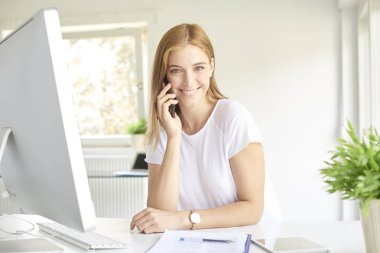 Güzel genç satış asistanı iş kadını yapma çağrısı ve modern bir ofiste bilgisayar önünde oturma sırasında biraz evrak işi yapıyor. 