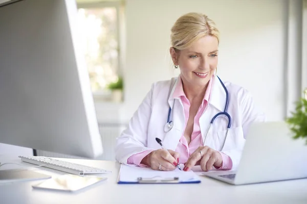 Närbild Leende Äldre Kvinnliga Läkare Använder Sin Laptop Och Skriva — Stockfoto