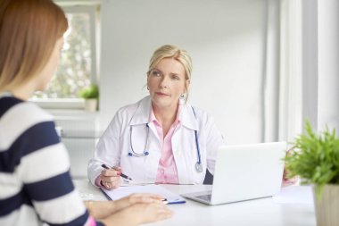 Kadınla konuşurken ve doktorun odasında tıbbi rapor yazma kadın doktor doz. 