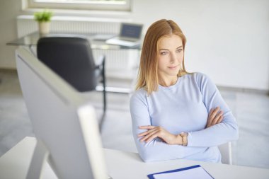 Ofis masası, katlanmış silah ile oturan bir düşünme genç kadın yüksek açı çekim.