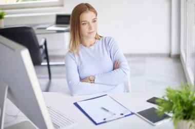 Modern ışık ofiste pc ile masaya oturan güzel genç iş kadını 