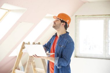 Genç Mühendis laptop süre ayakta inşaat sahasında ve çalışma elinde tutan çekim.