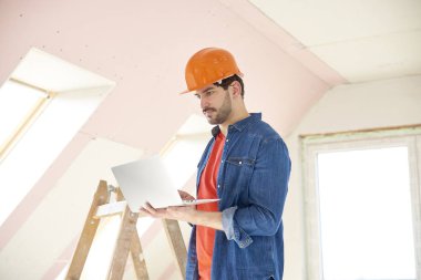 Genç Mühendis laptop süre ayakta inşaat sahasında ve çalışma elinde tutan çekim.