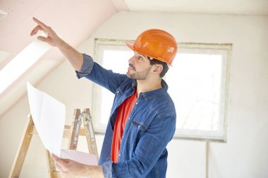 Dizüstü elinde tutan ve inşaat sahasında dururken bir şey gösteren genç bir mühendis kadeh.