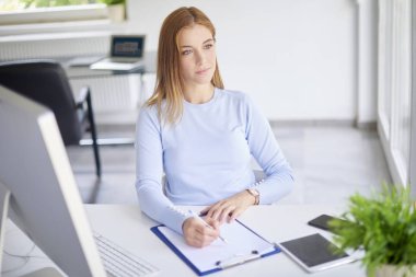 Ofiste oturan ve biraz evrak işi yapıyor genç işkadını yüksek açı çekim. 