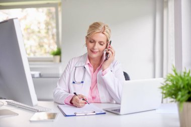 Cep telefonu kullaranarak ve onu hasta ile danışmanlık güzel yaşlı kadın doktor doz. 