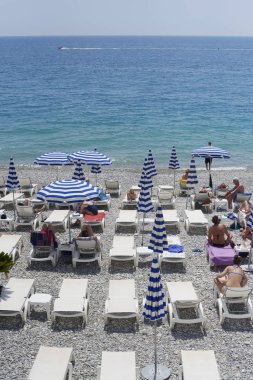Nice, Fransa -26 2018 olabilir: Görünümünü şemsiye ve şezlong mavi ve beyaz çizgili ile Promenade des Anglais'e Akdeniz'de Nice, Fransız Rivierası boyunca altında çakıl plaj