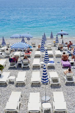 Nice, Fransa -26 2018 olabilir: Görünümünü şemsiye ve şezlong mavi ve beyaz çizgili ile Promenade des Anglais'e Akdeniz'de Nice, Fransız Rivierası boyunca altında çakıl plaj