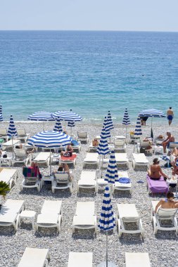 Nice, Fransa -26 2018 olabilir: Görünümünü şemsiye ve şezlong mavi ve beyaz çizgili ile Promenade des Anglais'e Akdeniz'de Nice, Fransız Rivierası boyunca altında çakıl plaj