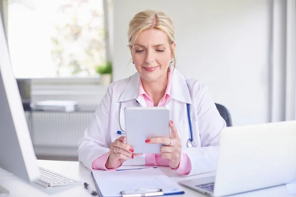 Ανώτερος Γυναίκα Γιατρό Χρησιμοποιώντας Touchpad Ενώ Κάθεται Στο Γιατροί Δωμάτιο — Φωτογραφία Αρχείου