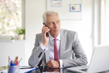 Smartphone içinde office çalışma laptop süre konuşurken çift üst düzey iş adamı