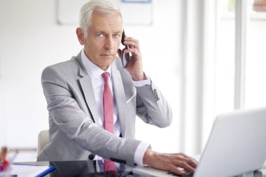 Smartphone içinde office çalışma laptop süre konuşurken çift üst düzey iş adamı