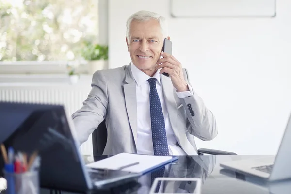 オフィスで作業ノート パソコン スマート フォンで話しているエグゼクティブの上級ビジネスマン — ストック写真
