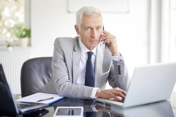 Ejecutivo Empresario Senior Hablando Teléfono Inteligente Mientras Trabaja Portátil Oficina —  Fotos de Stock