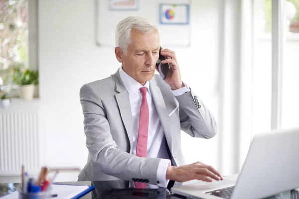 Ejecutivo Empresario Senior Hablando Teléfono Inteligente Mientras Trabaja Portátil Oficina —  Fotos de Stock