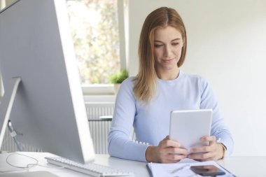 Genç işkadını ofis büro dizüstü bilgisayar önünde, dijital tablet kullanma