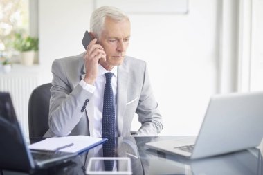 Smartphone içinde office çalışma laptop süre konuşurken çift üst düzey iş adamı