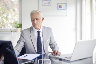 Ofis masası, dizüstü bilgisayar üzerinde çalışan ve yeni projede çalışan üst düzey iş adamı