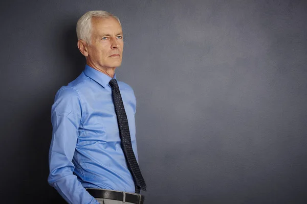 stock image Confident senior man looking thoughtfully while standing and grey wall.