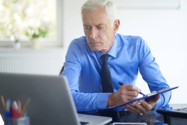 Ofis Masası oturma ve sunu üzerinde çalışan bazı evrak işi careworn üst düzey iş adamı. 