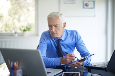 Ofis Masası oturma ve sunu üzerinde çalışan bazı evrak işi yakışıklı üst düzey iş adamı. 