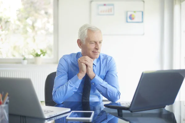 Portret Senior Biznesmen Wyglądający Zamyślony Siedząc Przy Biurku Pomocą Jego — Zdjęcie stockowe