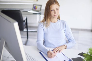 Ofis masa başında oturan bir şey yazma genç mali Yardımcısı işkadını yüksek açı çekim.