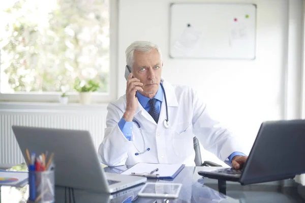 Doctor Masculino Sentado Mesa Sala Consulta Hablando Por Teléfono Mirando — Foto de Stock
