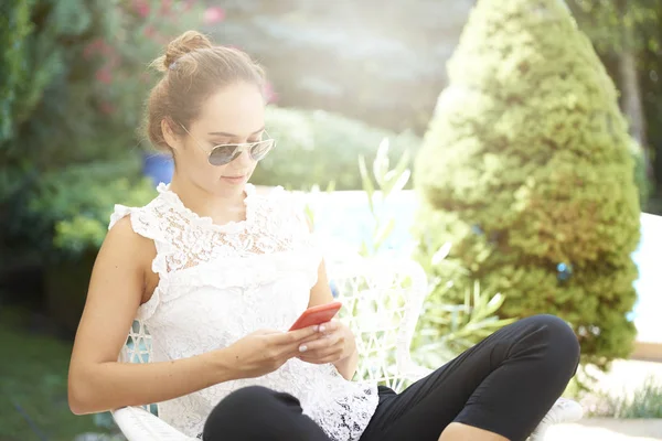 屋外で座りながら若い女性テキストメッセージングのショット — ストック写真