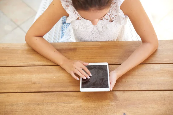 机に座って 彼女の手でデジタル タブレットを保持している若い女性のハイアングル ショット — ストック写真