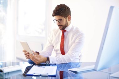Genç işadamı ise ofiste oturan ve yeni projede çalışan dijital tablet kullanarak çekim. 