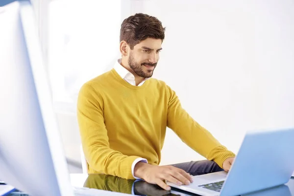 オフィスでノート パソコンでの作業中にシャツとセーターを着て青年実業家を笑顔 — ストック写真
