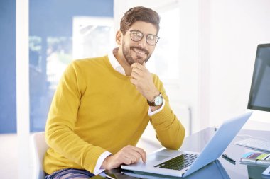 Mutlu genç işadamı ofis masa başında otururken diz üstü üzerinde çalışma. 