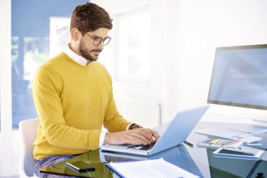 Diz üstü kullanarak ve bir şey ofiste oturma ve çalışma sırasında yazarak genç işadamı portresi. 