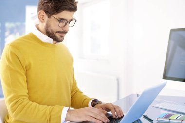 Diz üstü kullanarak ve bir şey ofiste oturma ve çalışma sırasında yazarak genç işadamı portresi. 