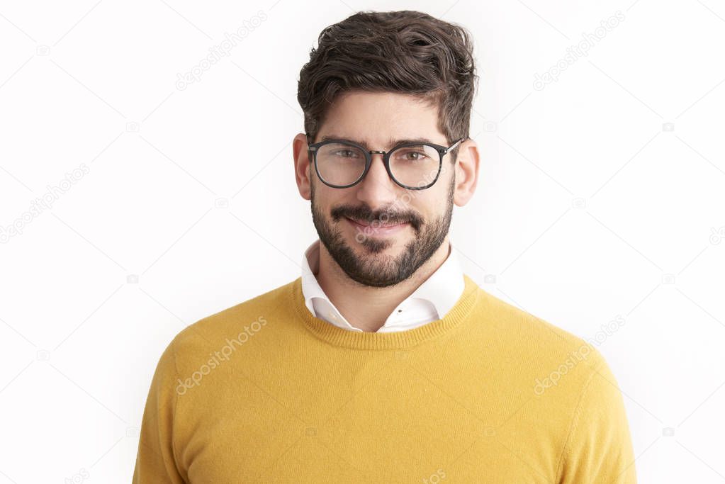 Close-up portrait shot of casual young businessman looking at camera and smiling while wearing glasses and sweater. Isolated on white background. 